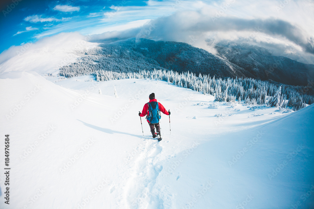 A man in snowshoes in the mountains in the winter.