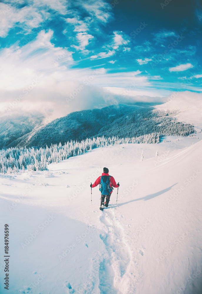 A man in snowshoes in the mountains in the winter.