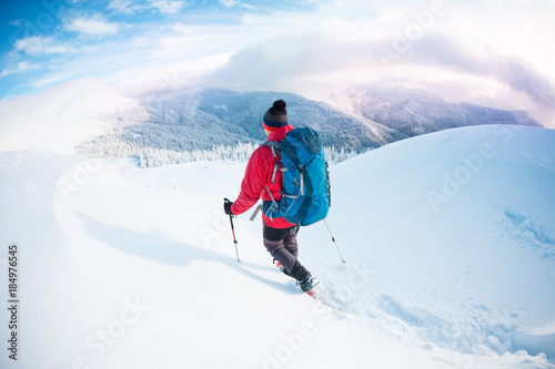 A man in snowshoes in the mountains in the winter.