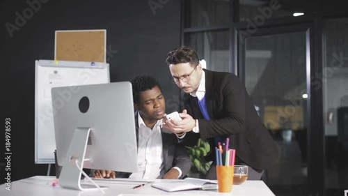 Boss shows his employee a pictures on the smartphone in the office