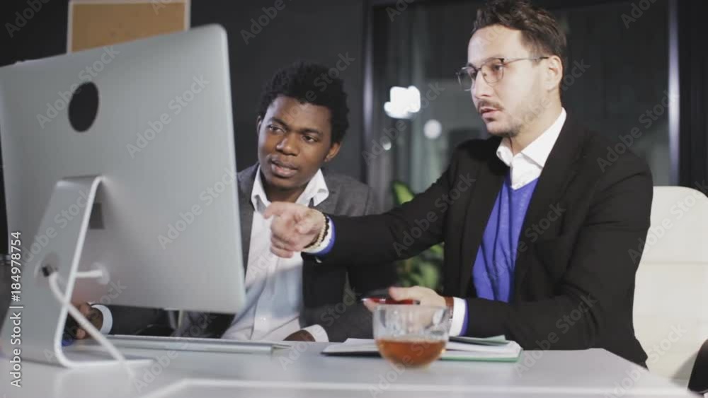 Two men in the office discussing the project in front of the computer Two men in the office discussing the project in front of the computer