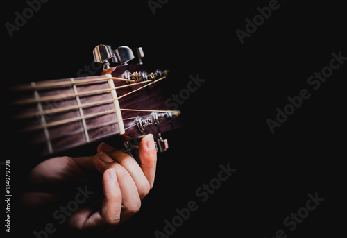 closeup male musician hands tuning acoustic guitar strings, isolated on black