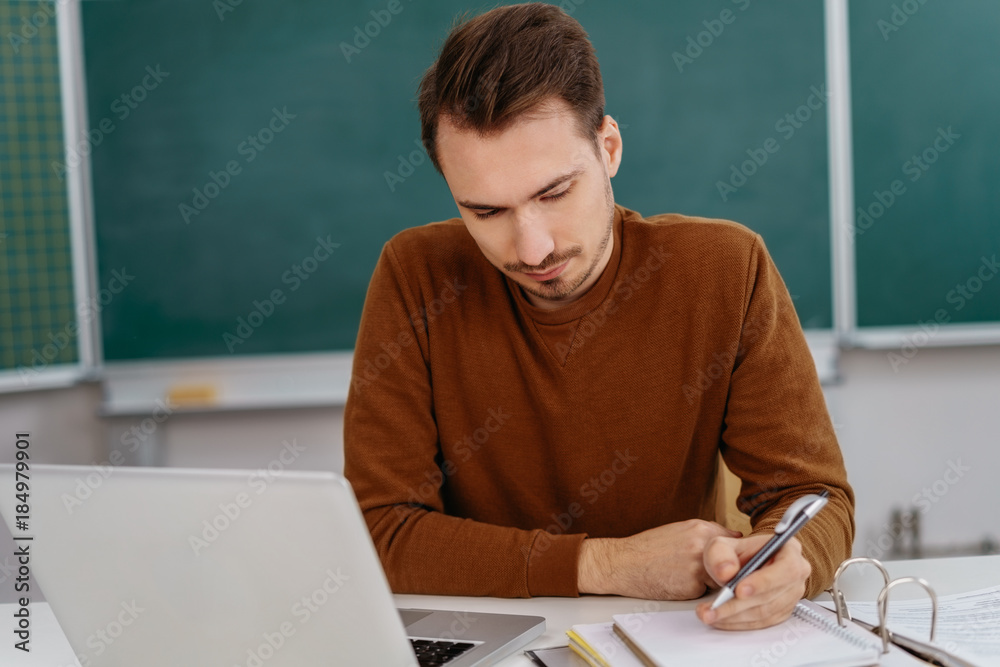 Teacher or male student sitting working in a class Teacher or male student sitting working in a class