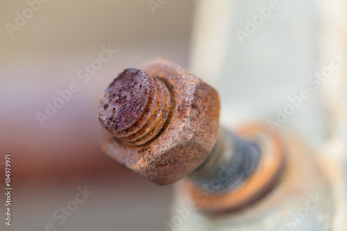 Close-up image of old rusty screw and bolt on steel surface with blurred background photo