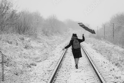 A cute young girl holds umbrella in the hands of the winter season
