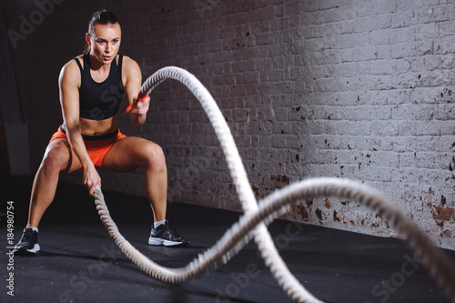 Fotografie, Tablou Woman training with battle rope in cross fit gym