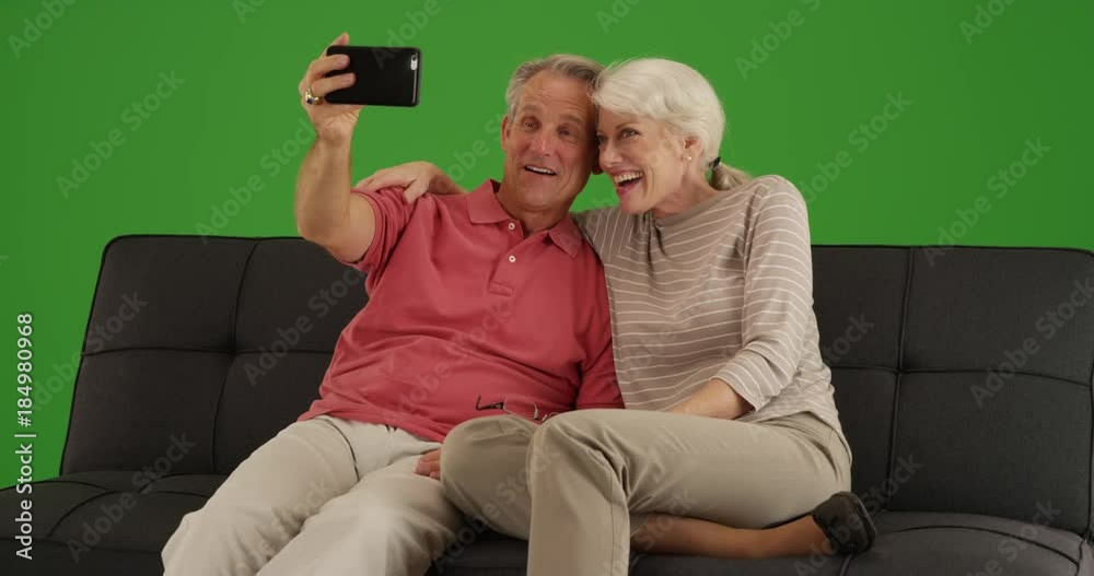 Cute senior couple taking a selfie with smartphone at home on green screen. On green screen to be keyed or composited. Cute senior couple taking a selfie with smartphone at home on green screen. On green screen to be keyed or composited.