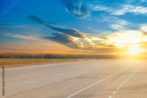 Beautiful evening landscape of runway, airstrip in the airport terminal ready for airplane landing or taking off with dramatic cloudy sunset background. Travel aviation future concept at golden hour.