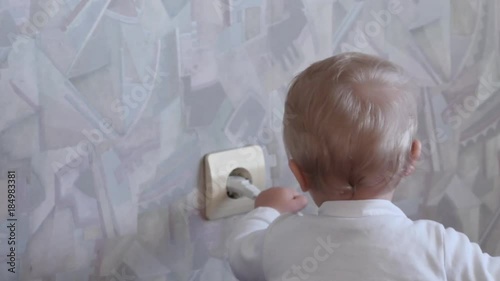 funny cute 9-10 months old baby pulls out the plug from power socket photo