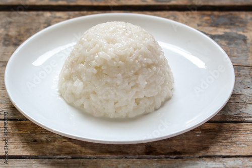 boiled round rice on a white plate, on a wooden surface