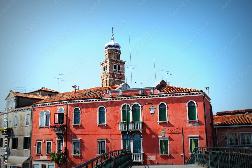 Colorful residential buildings and campanile of church San Pietro Martire in Burano island, Venice lagoon