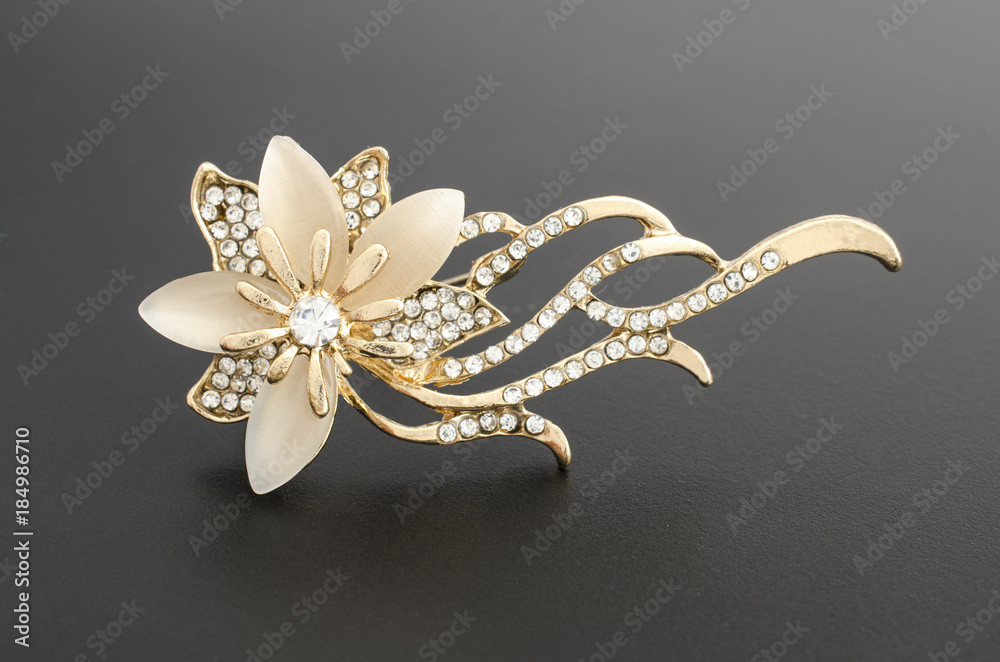 gold brooch flower with gems and moon stone isolated on black