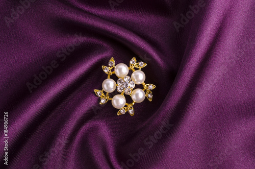 gold brooch flower with pearl isolated on silk