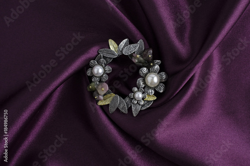 round brooch with flowers and pearls on white silk