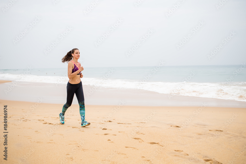 Woman is jogging along the seashore on an overcast day Woman is jogging along the seashore on an overcast day