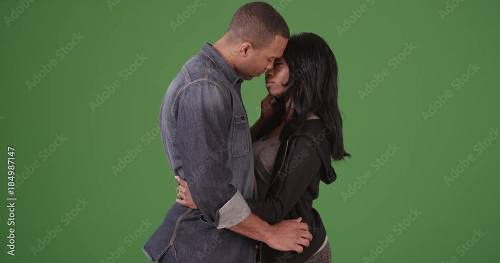 Young black couple kissing each other on green screen. On green screen to be keyed or composited. 