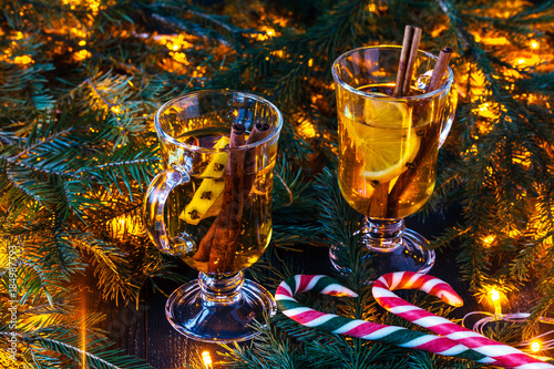 New Year's mulled wine in a glass on the background of twigs, candles and garlands.