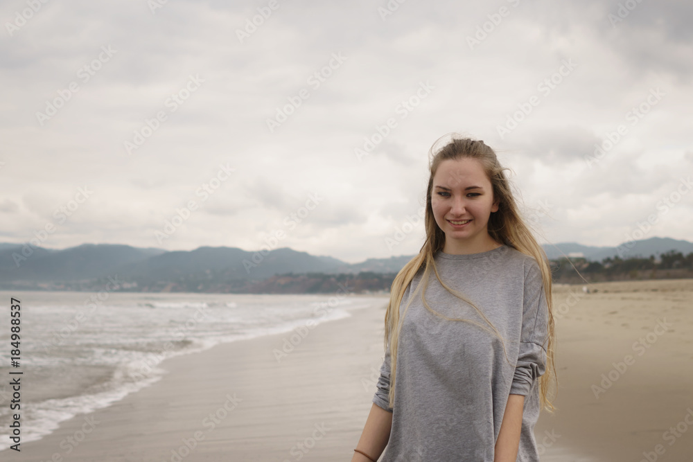 teen girl walking on Santa Monica beach in cloudy november teen girl walking on Santa Monica beach in cloudy november