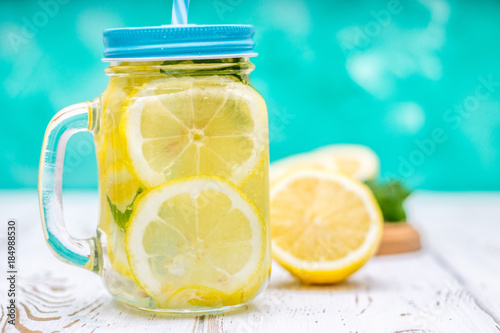 Banks with handles with cold lemonade on a white wooden background. Lemons. © detry26