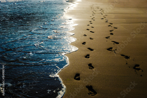 Two pairs of footprints in the sand on the beach photo