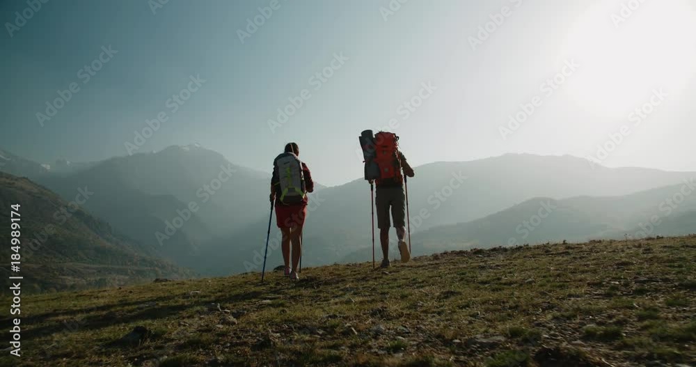 Hiking couple walking on trail. Healthy lifestyle hiker people walking in mountains. Young woman and man travel to honeymoon, steadycam shot