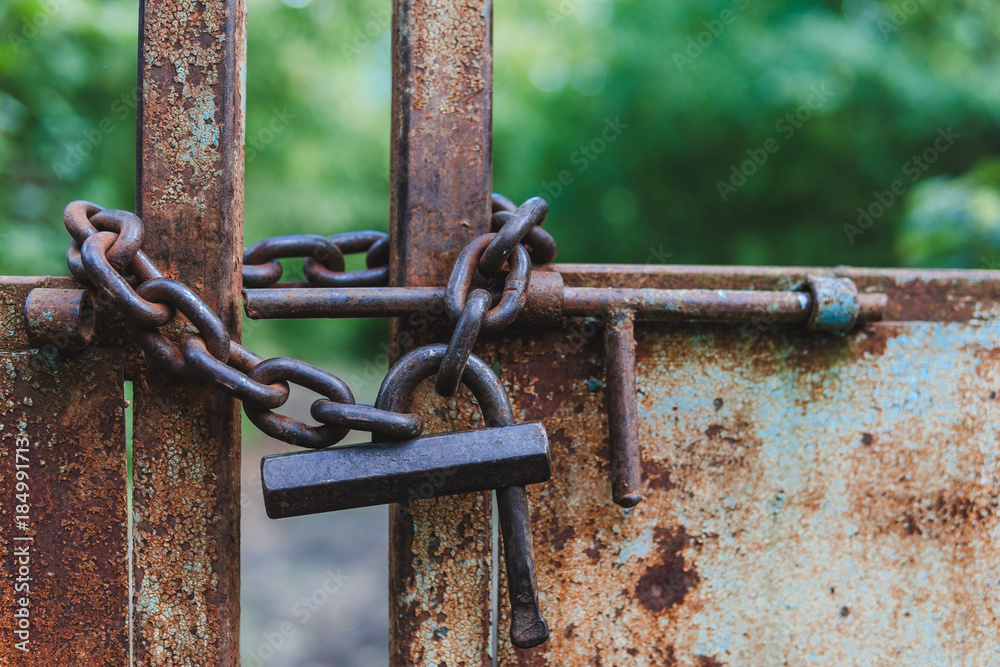 Rusty metal gate closed with padlock - concept image