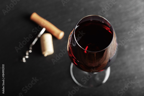 wine glass of red wine with a corkscrew. On a black wooden background. with space for text