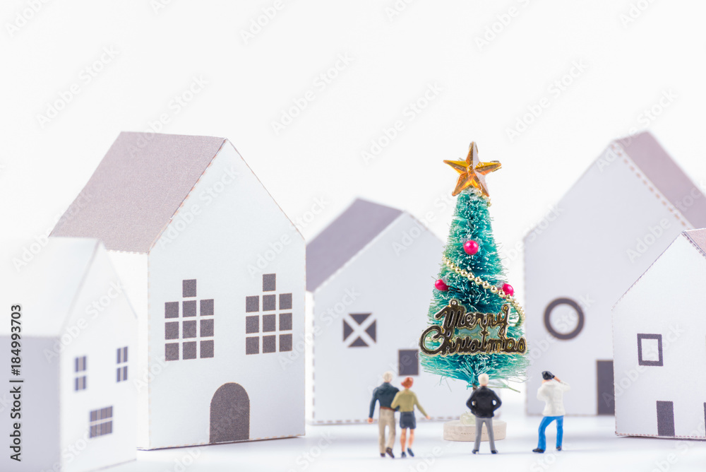 Miniature tiny people toys enjoy with christmas tree in the paper house town at christmas day isolated on white background with copy space.Theme Christmas day background.