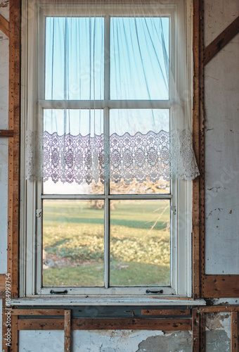 Window with curtain of old demolition house with rural view.