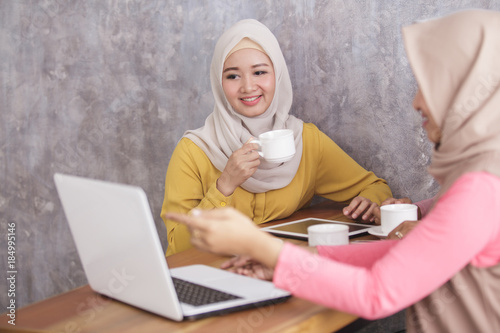 beautiful muslim women explaining project on laptop to her partn