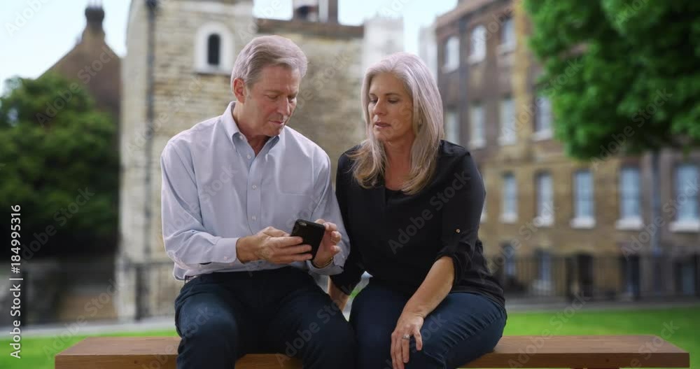 Old man and woman sitting on bench in London chat about recent event 