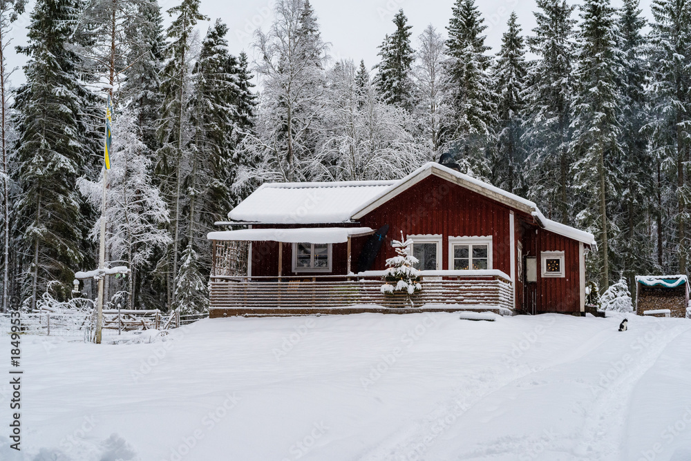 A little red cabin in a forest covered in snow A little red cabin in a forest covered in snow