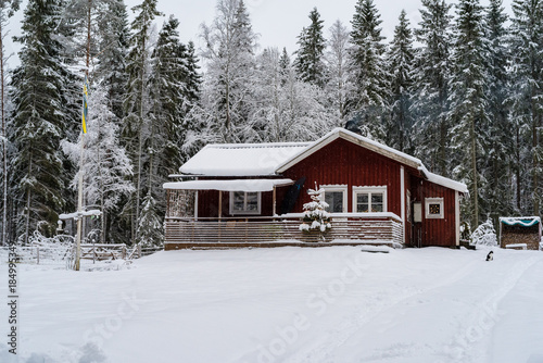 A little red cabin in a forest covered in snow © Jonas