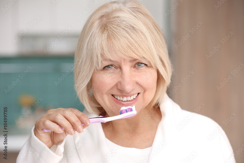 Mature woman cleaning teeth at home Mature woman cleaning teeth at home