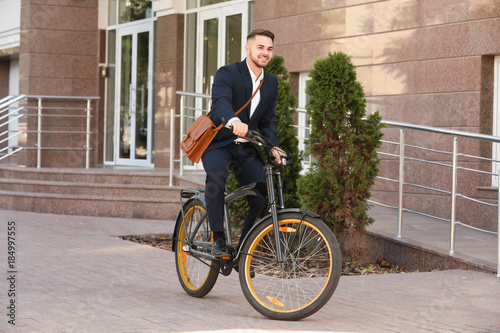 Fototapeta Naklejka Na Ścianę i Meble -  Young handsome businessman riding bicycle outdoors