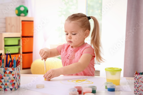 Little cute girl painting a...