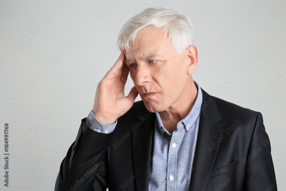 Portrait of thoughtful mature man in dark suit on light background Portrait of thoughtful mature man in dark suit on light background