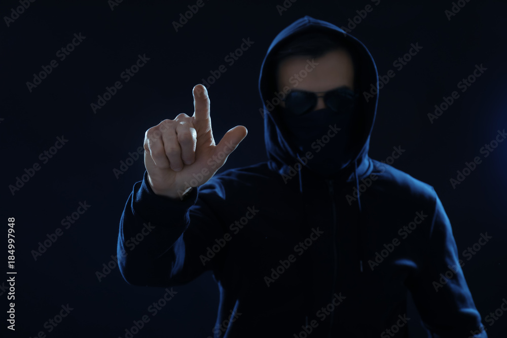 Hacker pushing button on virtual screen against dark background