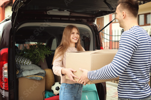 Canvas Print Young couple unloading boxes from their car on moving day