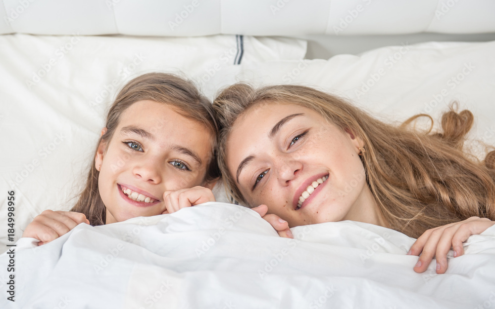 Happy mother with daughter lie on the bed under the blanket. Top view Happy mother with daughter lie on the bed under the blanket. Top view