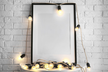Mockup of blank frame with garland on table
