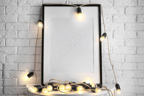 Mockup of blank frame with garland on table