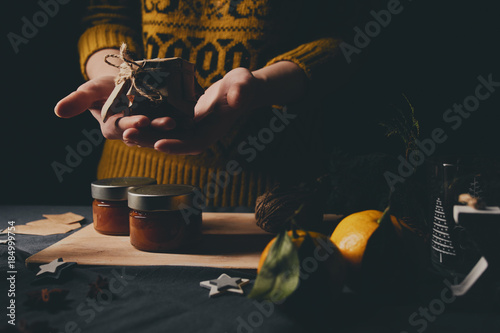 Female hands cooking orange jam for Christmas gifts