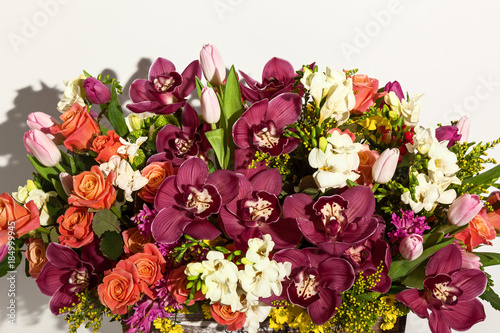 composition of flowers from pink roses, burgundy orchids, red tulips, hyacinth and hrzemtem. Flower Arrangement in a box for a girl of roses, tulips and orchids on a white background