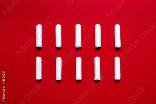 Menstruation. Rows of tampons on a red background