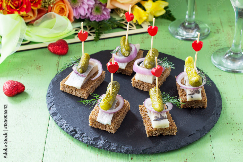 Canapes with rye bread, herring and pickles on a festive table. Valentine's day concept or wedding. Canapes with rye bread, herring and pickles on a festive table. Valentine's day concept or wedding.