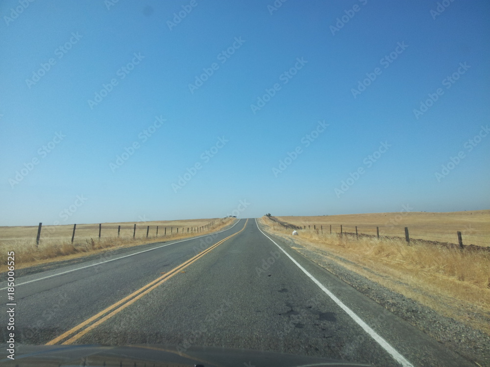 Desert road with yellow road lines and clear blue sky 