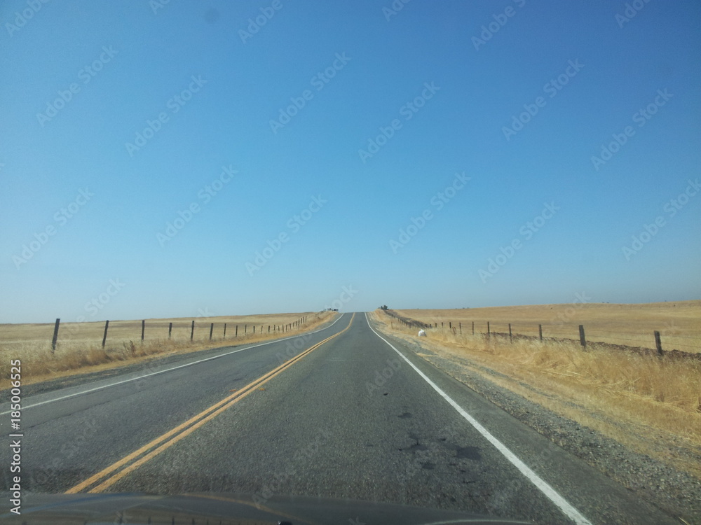 Desert road with yellow road lines and clear blue sky Desert road with yellow road lines and clear blue sky