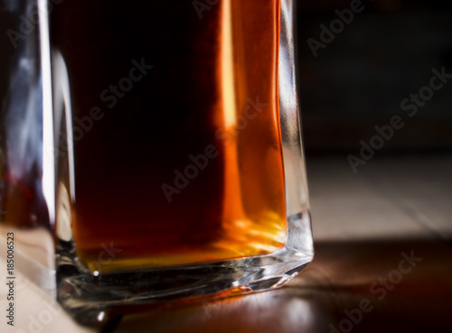 Whiskey/Rom/liquor in a vintage bottle being lidt from the side - casting colored light and shadows on wooden floor   boards