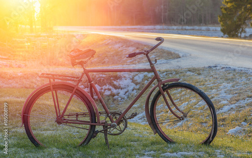 Old red rusty bicycle velo on the winter spring road.